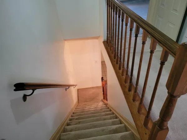 a view of staircase with railing and white walls