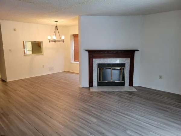 a view of an empty room with wooden floor fireplace and a window