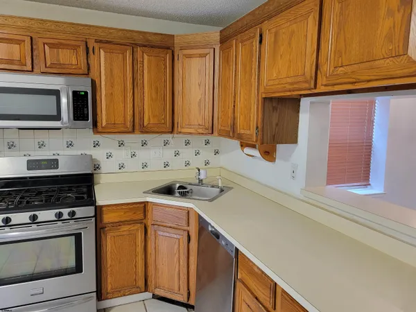 a kitchen with stainless steel appliances granite countertop a stove a sink and a microwave