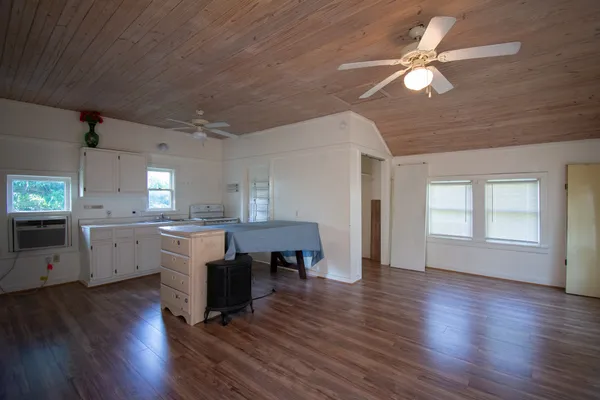 a open kitchen with cabinets a sink dishwasher a dining table and chairs with wooden floor