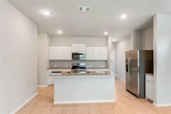 a kitchen with stainless steel appliances a refrigerator a stove a sink and a microwave