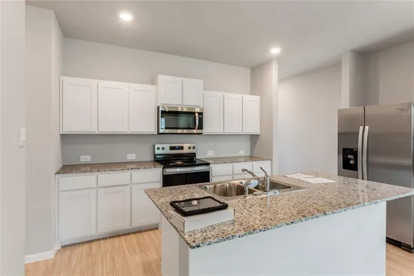 a kitchen with granite countertop a sink stove and refrigerator