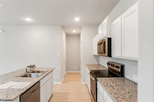 a large kitchen with granite countertop a sink and a stove top oven with wooden floor
