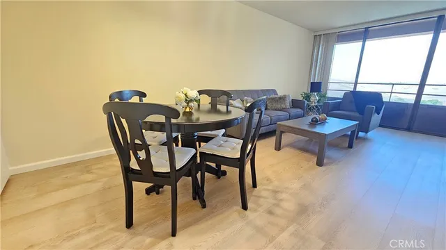 a view of a livingroom and dining room with furniture wooden floor and a floor to ceiling window