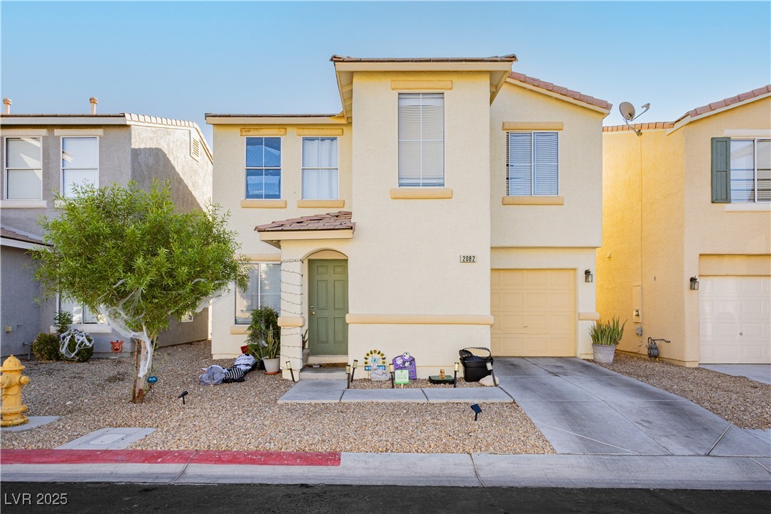 View of front of house with driveway, stucco siding, a tile roof, and an attached garage