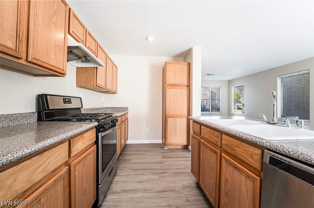 2082 Pillar Pointe Street Las Vegas, NV 89115 - Photo 16 of 18 Kitchen with stainless steel appliances, under cabinet range hood, light wood finished floors, brown cabinets, and recessed lighting