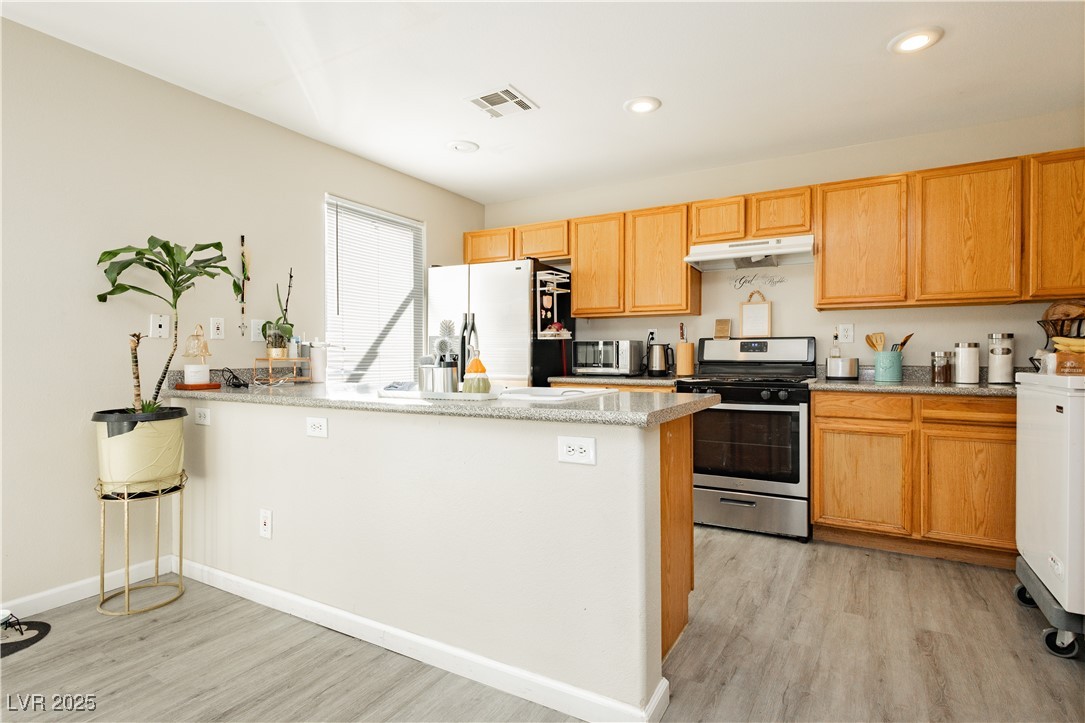 2082 Pillar Pointe Street Las Vegas, NV 89115 - Photo 8 of 18 Kitchen featuring stainless steel appliances, light wood-type flooring, light stone counters, recessed lighting, and a peninsula