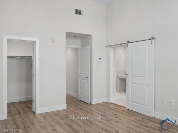 a view of an empty room with closet and wooden floor