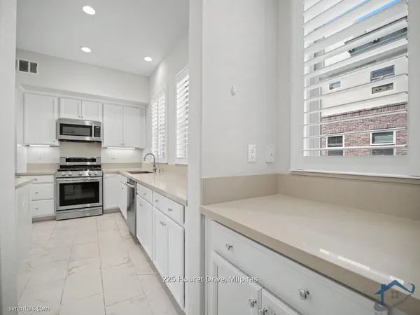 a kitchen with kitchen island white cabinets appliances and a window