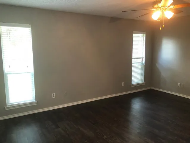 an empty room with wooden floor and windows in it