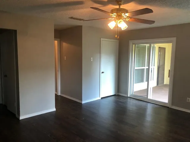 a view of an empty room with window and wooden floor
