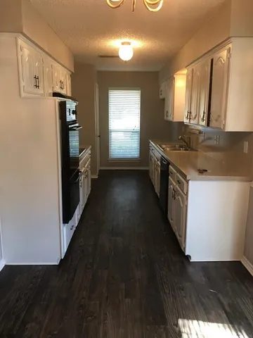 a kitchen with granite countertop a refrigerator a sink dishwasher stove and wooden cabinets