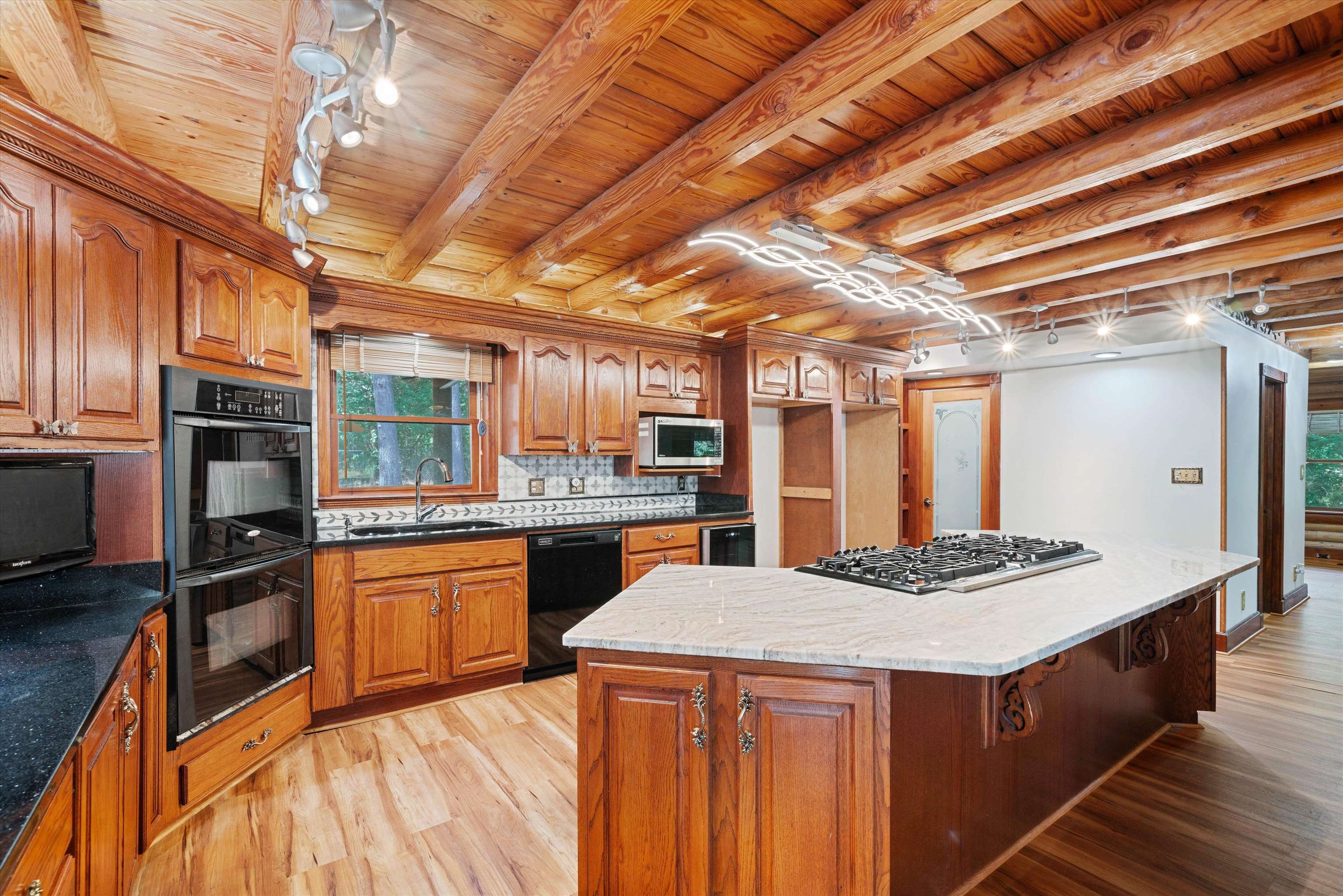 245 Metro Road Eads, TN 38028 - Photo 11 of 33 Kitchen with black appliances, beamed ceiling, light stone countertops, and light wood-type flooring