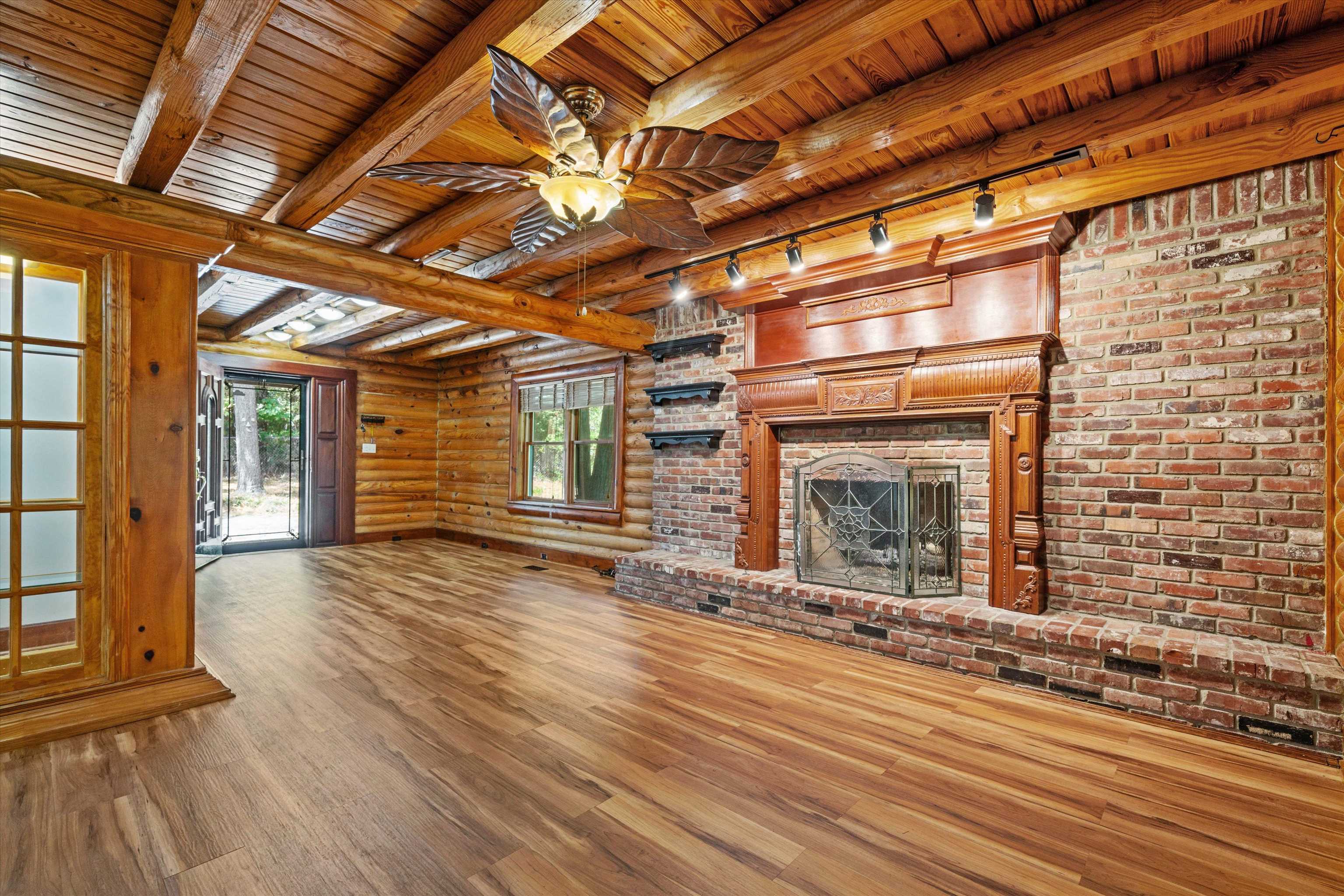 245 Metro Road Eads, TN 38028 - Photo 17 of 33 Unfurnished living room with hardwood / wood-style flooring, a brick fireplace, wood ceiling, ceiling fan, and beam ceiling