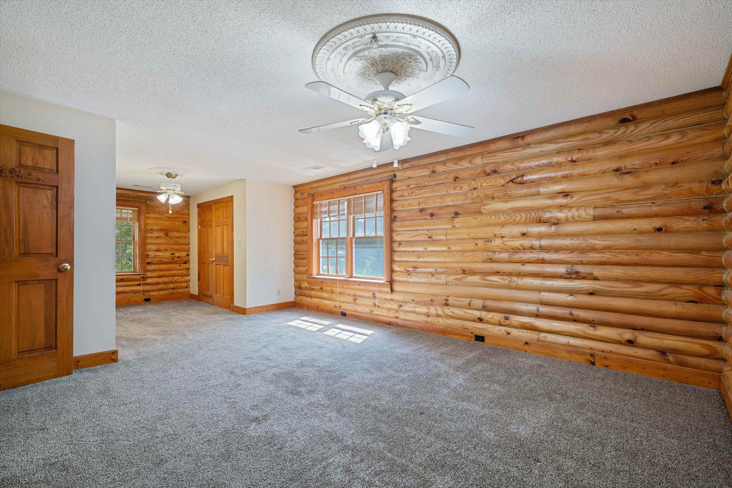 245 Metro Road Eads, TN 38028 - Photo 23 of 33 Carpeted spare room featuring ceiling fan, log walls, and a textured ceiling