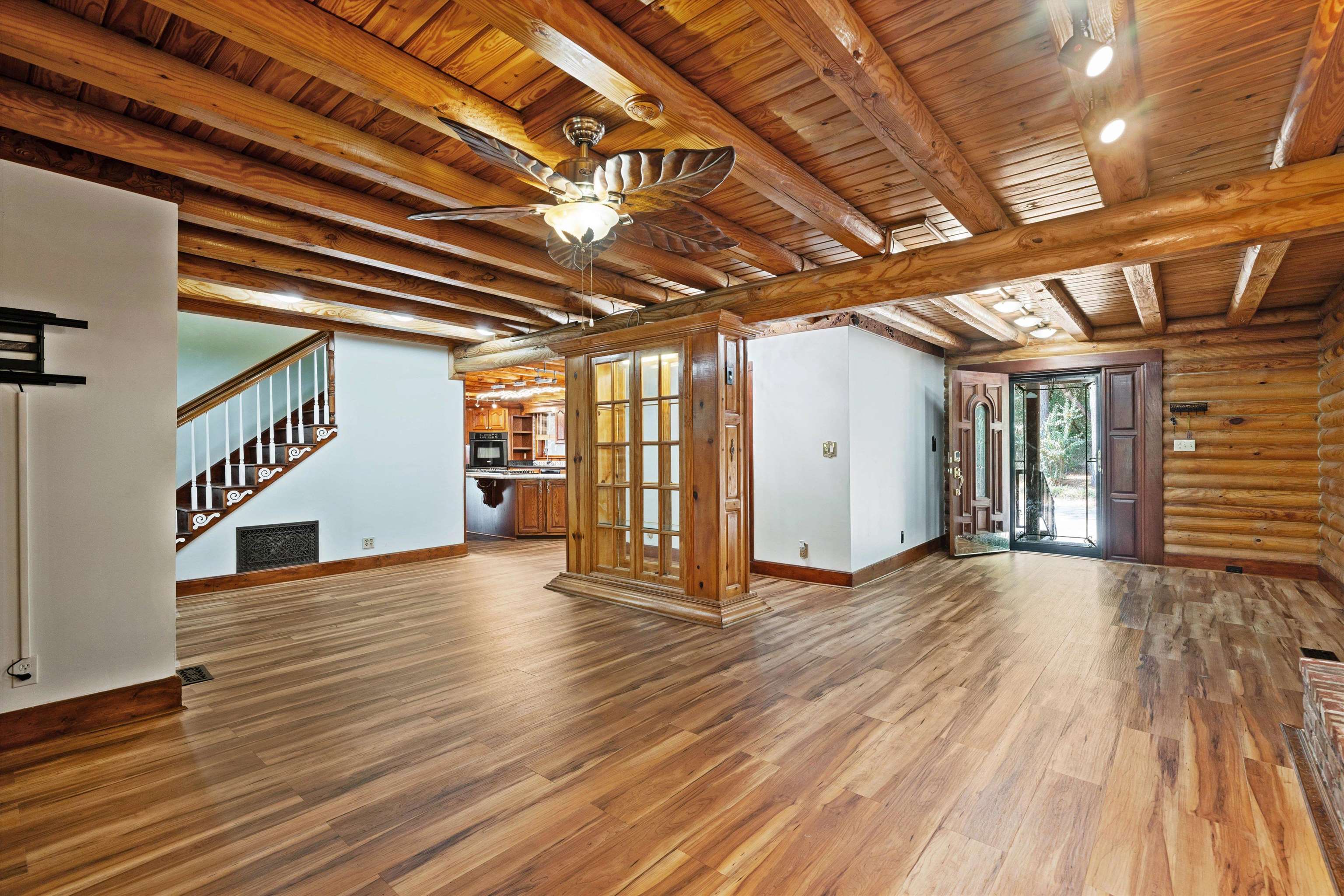 245 Metro Road Eads, TN 38028 - Photo 7 of 33 Unfurnished living room featuring wooden ceiling, wood-type flooring, beam ceiling, ceiling fan, and rustic walls