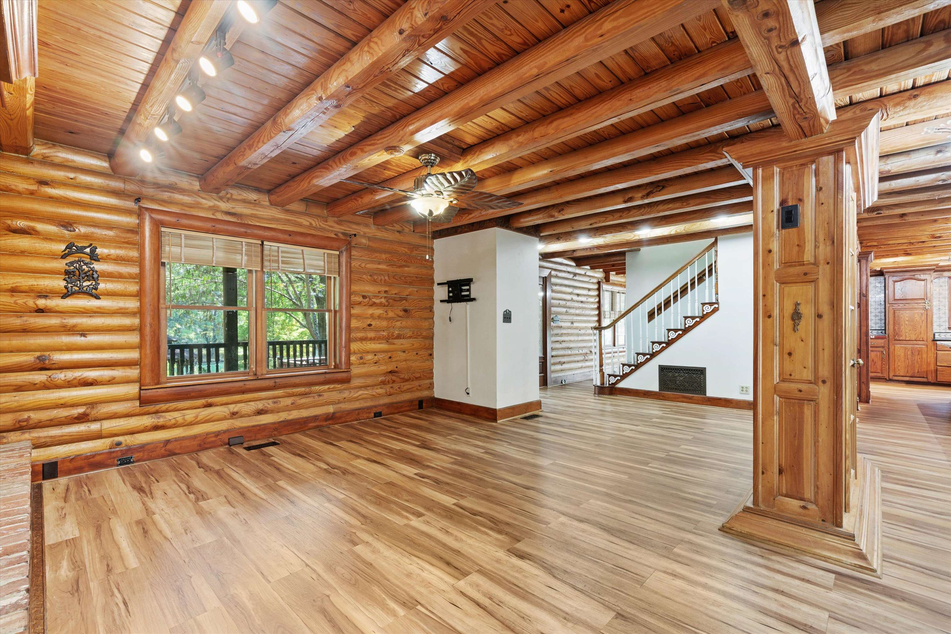 245 Metro Road Eads, TN 38028 - Photo 8 of 33 Unfurnished living room with light wood-type flooring, track lighting, beamed ceiling, wooden ceiling, and log walls