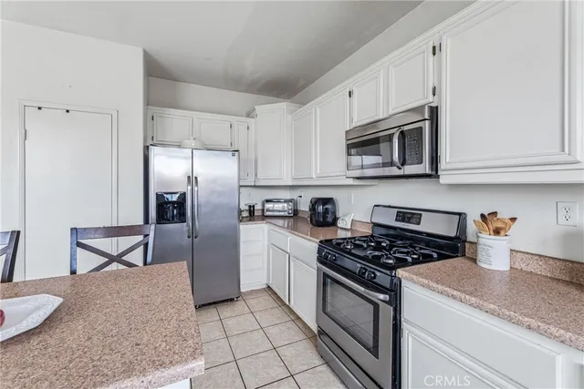 a kitchen with stainless steel appliances granite countertop a stove a refrigerator and a white cabinets