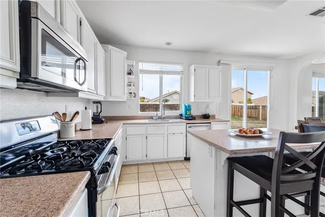 a kitchen with stainless steel appliances a sink a stove a table and chairs