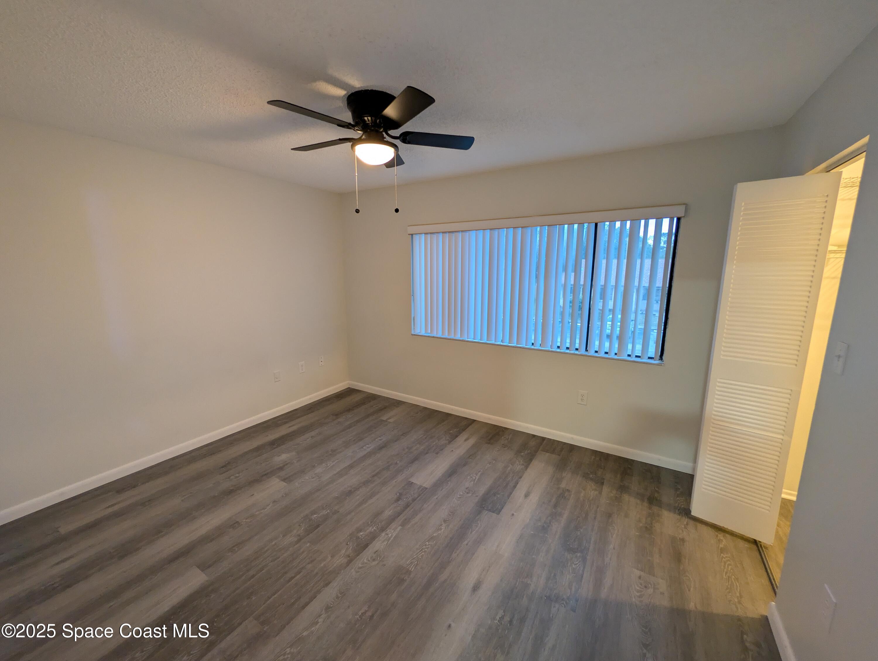 4801 Sisson Road Titusville, FL 32780 - Photo 11 of 21 an empty room with wooden floor fan and windows