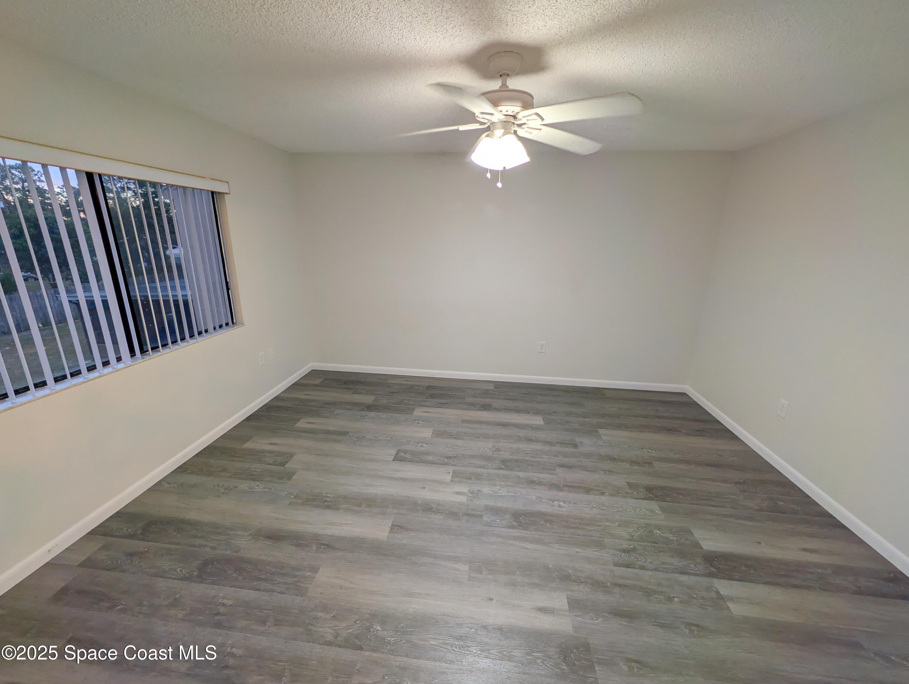 4801 Sisson Road Titusville, FL 32780 - Photo 14 of 21 an empty room with wooden floor and chandelier fan