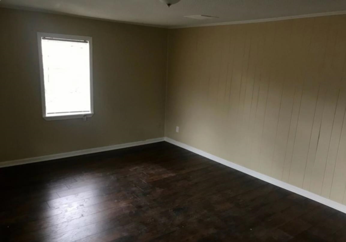 Unfurnished room featuring dark wood-style floors and wood walls