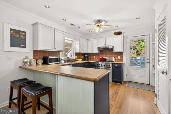 a kitchen with granite countertop a stove top oven a sink dishwasher and a refrigerator with wooden floor