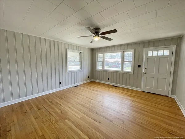 an empty room with wooden floor and windows