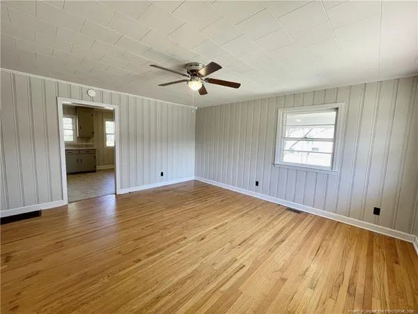 a view of empty room with wooden floor and fan