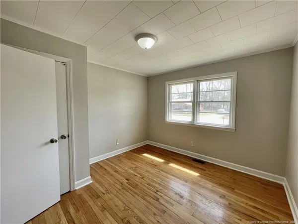 an empty room with wooden floor and windows