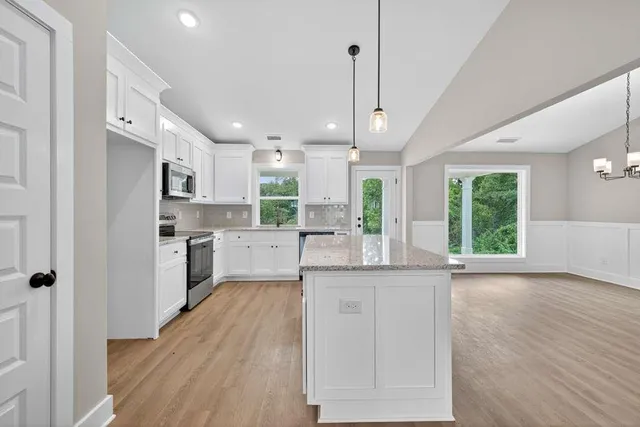 a kitchen with stainless steel appliances kitchen island hardwood floor sink stove and a window
