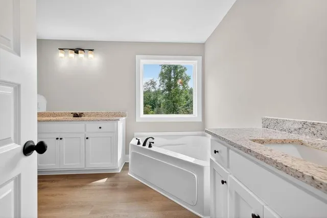a spacious bathroom with a tub sink and mirror