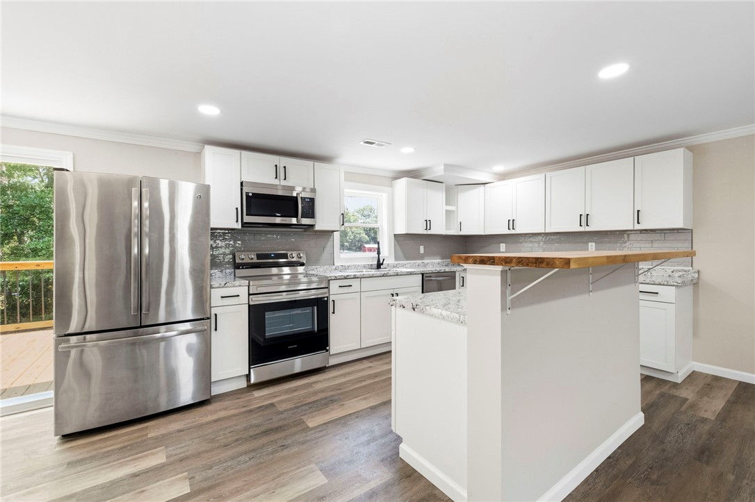 418 Old River Road Pelzer, SC 29669 - Photo 6 of 29 A well-appointed kitchen features ample counter space, contemporary white cabinetry, and a practical island with seating.