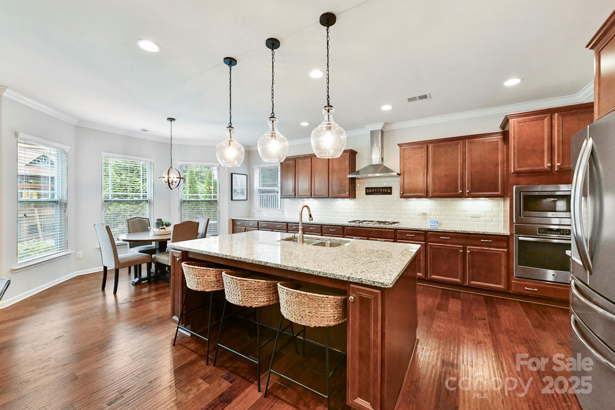 1084 Cameron Creek Parkway Tega Cay, SC 29708 - Photo 7 of 25 a kitchen with kitchen island granite countertop wooden floors and stainless steel appliances