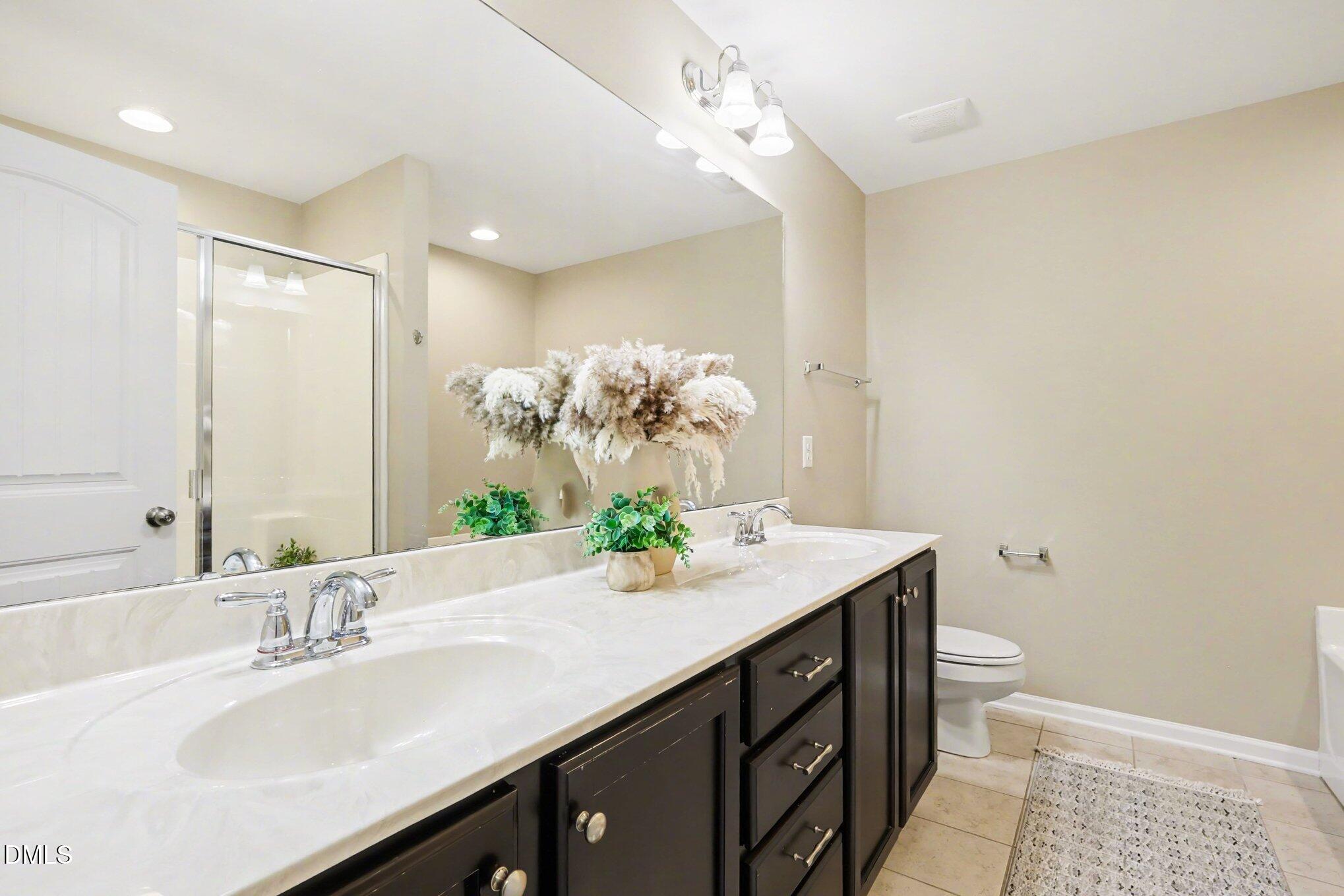 2409 Memory Ridge Drive Raleigh, NC 27606 - Photo 23 of 36 a bathroom with a granite countertop sink a toilet and a mirror