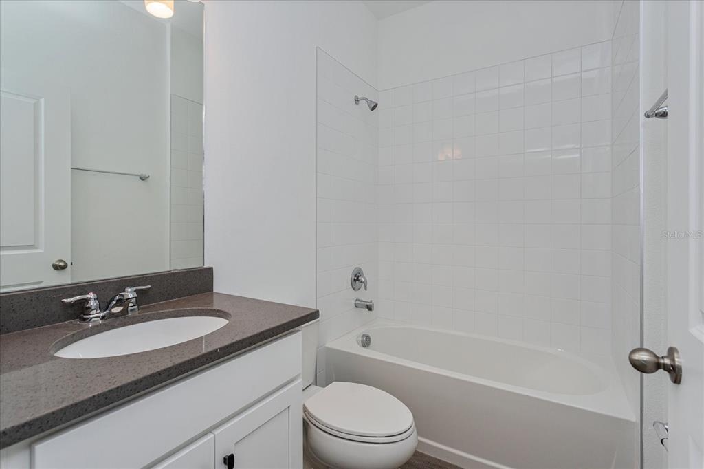 1010 Swamp Chestnut Loop Lady Lake, FL 32159 - Photo 14 of 22 a bathroom with a granite countertop sink toilet a mirror and shower