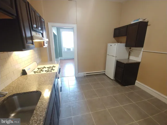 a view of an empty room with wooden floor and a sink