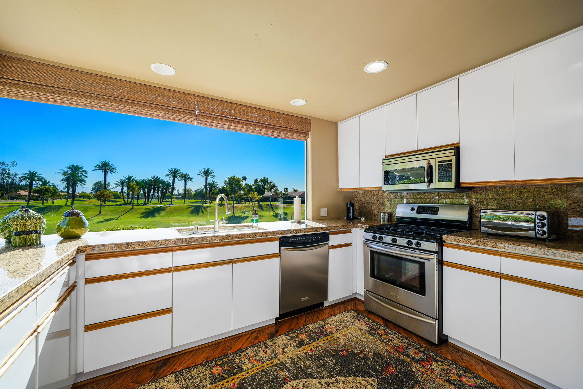 55 Colonial Drive Rancho Mirage, CA 92270 - Photo 10 of 31 a kitchen with stainless steel appliances granite countertop a stove a sink and a microwave
