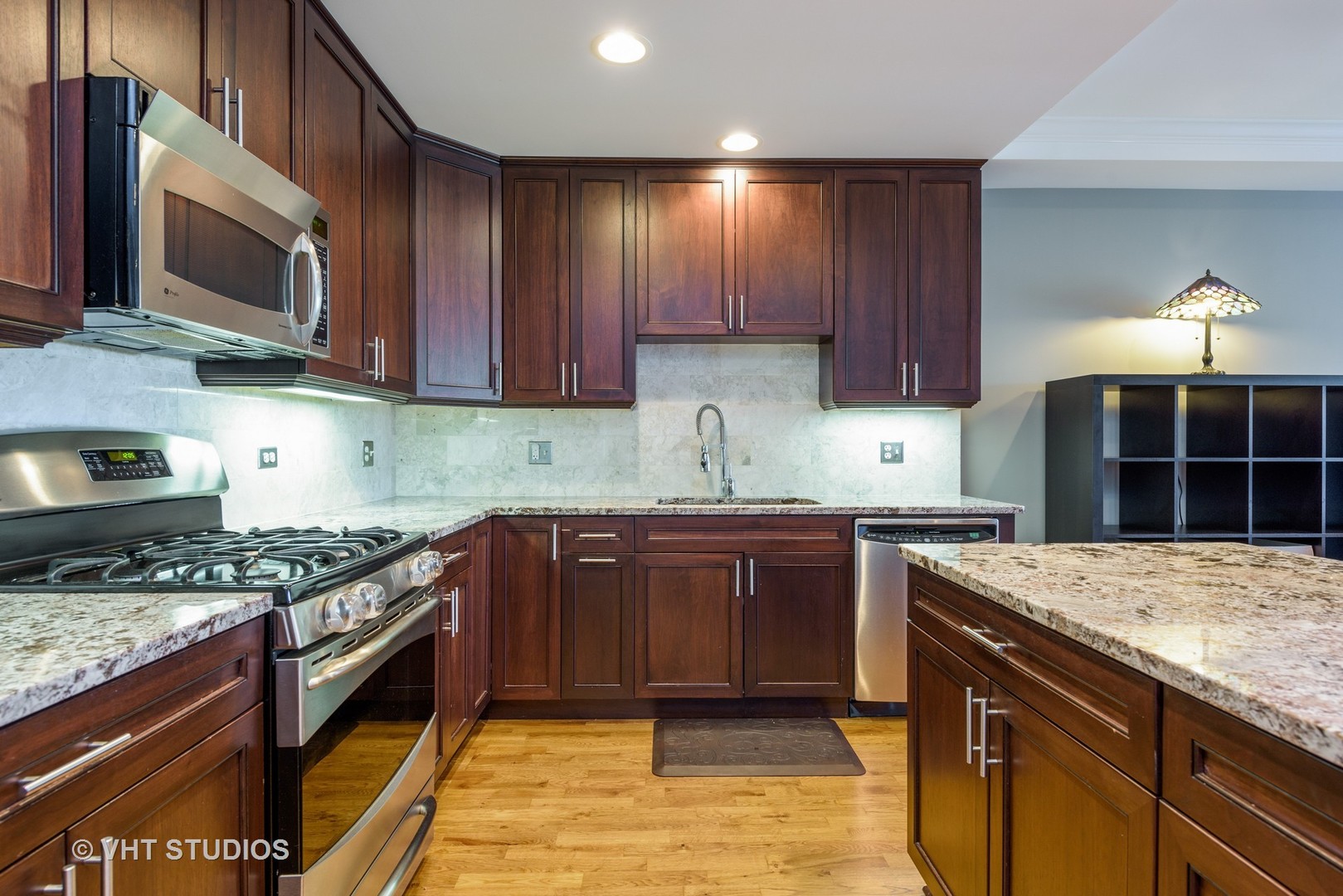 1909 West Diversey Parkway, Unit 302 Chicago, IL 60614 - Photo 5 of 12 a kitchen with stainless steel appliances granite countertop wooden cabinets stove top oven and sink