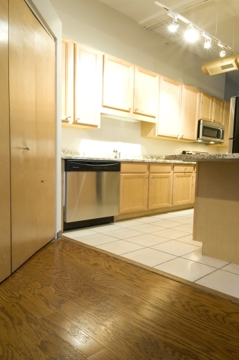 801 South Wells Street, Unit 311 Chicago, IL 60607 - Photo 8 of 16 a view of a kitchen with kitchen island a sink wooden floor and a counter top space