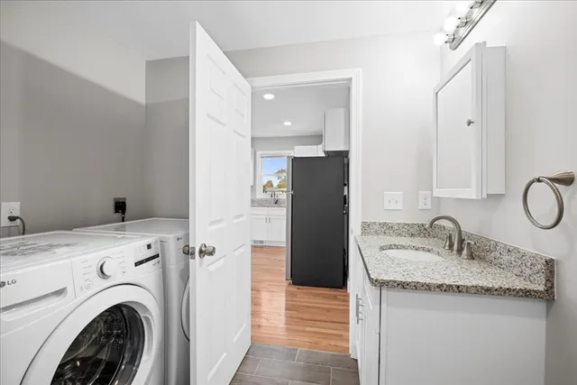 a bathroom with a granite countertop sink and a washer dryer