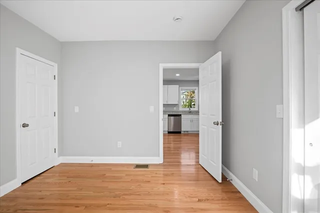 a view of a hallway with wooden floor and a living room