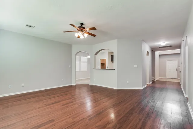 a view of empty room with wooden floor and fan