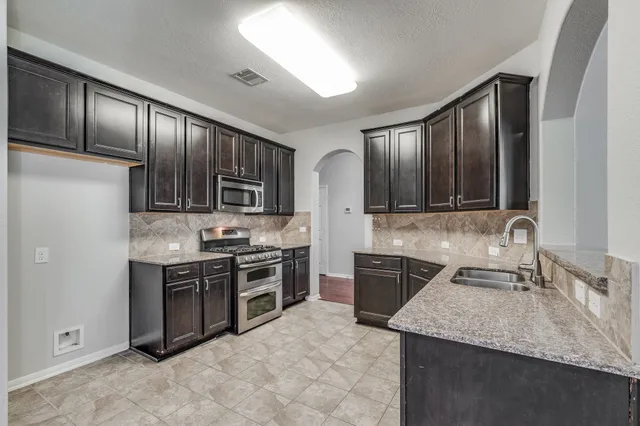 a kitchen with stainless steel appliances granite countertop wooden cabinets a stove top oven a sink and dishwasher