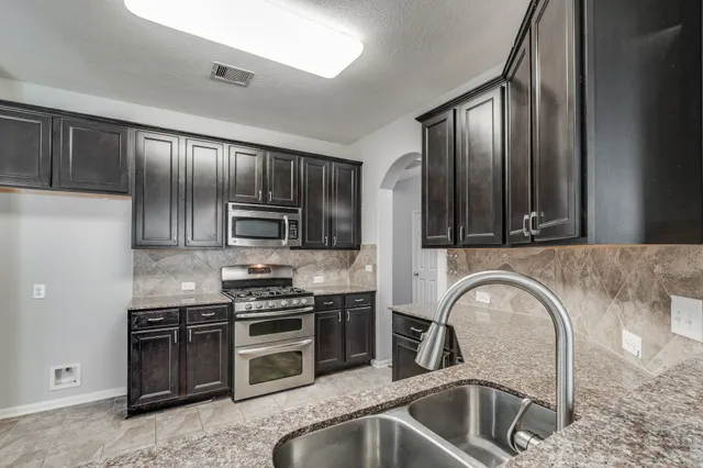 a kitchen with stainless steel appliances granite countertop a stove a sink and a refrigerator