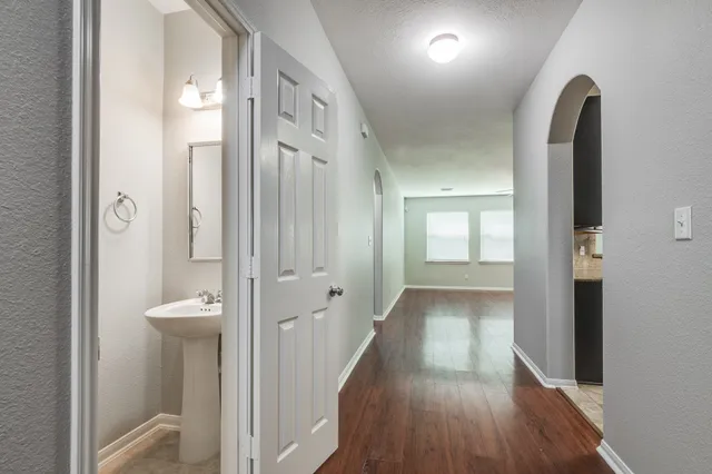 a view of a hallway with wooden floor and a bathroom