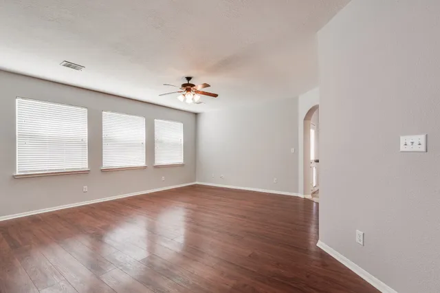 an empty room with wooden floor and windows