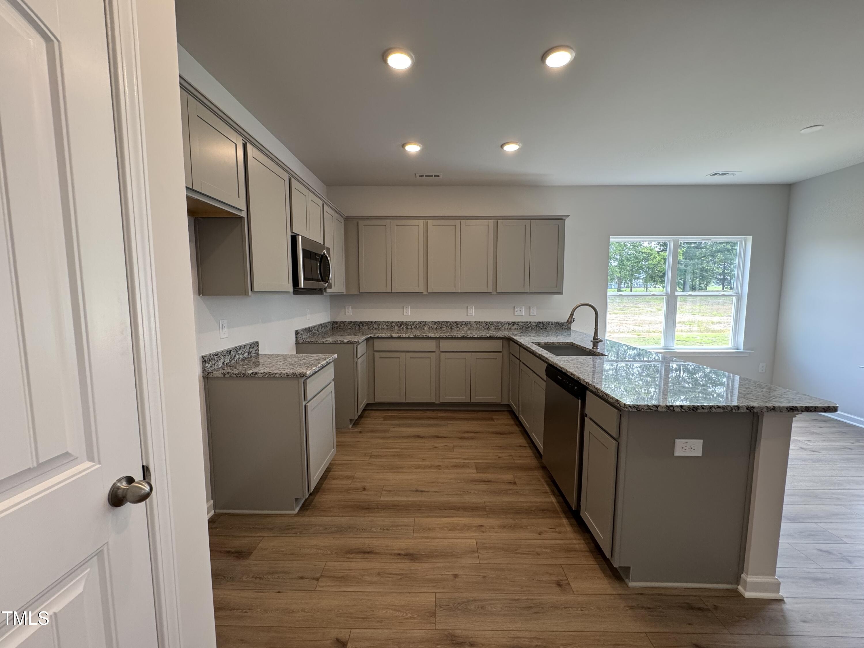 51 Commons Circle Clayton, NC 27520 - Photo 6 of 31 a large kitchen with stainless steel appliances granite countertop a stove top oven a sink dishwasher and a microwave oven on the wooden floor