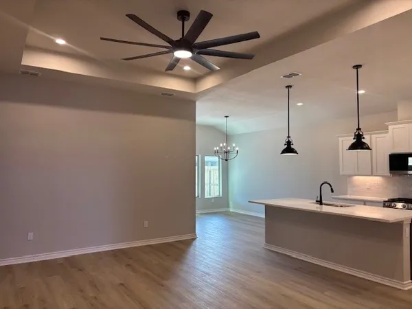 a view of a room with a sink wooden floor and a ceiling fan