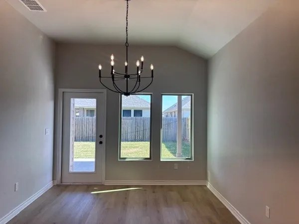 a view of a livingroom with a chandelier wooden floor and windows